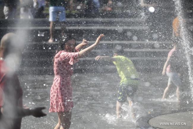 es gens se rafraîchissent dans une fontaine à New York aux Etats-Unis, le 2 juillet 2018. La température a atteint jusqu'à 35 degrés lundi dans la ville américaine. (Photo : Wang Ying)