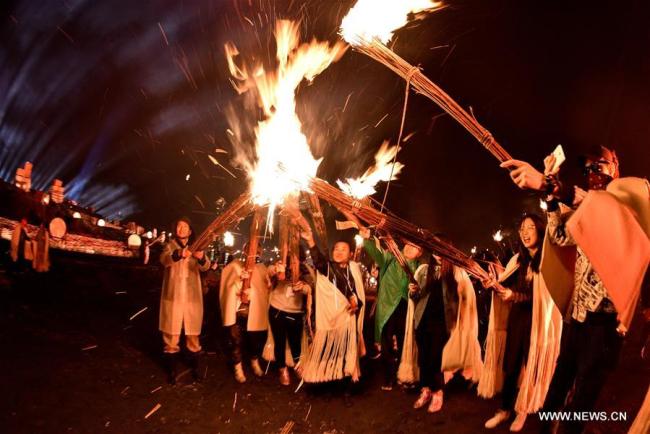 Des participants allument des torches lors de la fête des Torches de l'ethnie Yi dans le district de Zhaojue de la province du Sichuan (sud-ouest de la Chine), le 5 août 2018. Des membres de l'ethnie Yi et des touristes ont dansé et chanté ensemble pour célébrer l'événement. (Photo : Lyu Mingze)