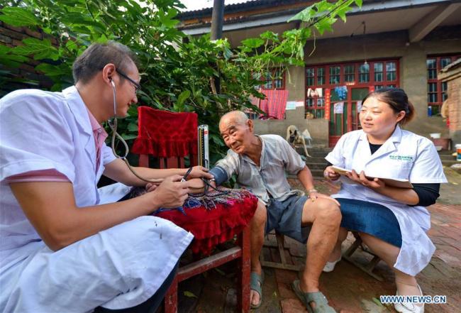 Les docteurs Zhai Dalong (à gauche) et Wang Cuihong (à droite) prennent la tension artérielle d'un patient du village de Xudi, dans le comté de Daming à Handan, dans la province du Hebei (nord), le 16 août 2018. Zhai et Wang sont mari et femme. Un grand nombre de praticiens médicaux sont actifs dans les zones rurales chinoises, où les soins de santé sont encore sous-développés. Pratiquant dans des conditions de travail défavorables, ils portent en eux l'esprit humanitaire et se sont consacrés à la santé des citoyens ruraux. La Chine a marqué sa première Journée des travailleurs médicaux le 19 août 2018. 