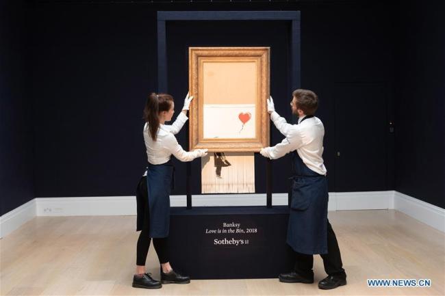 Le personnel de Sotheby's présente « L'amour est dans la poubelle » de Banksy à Londres