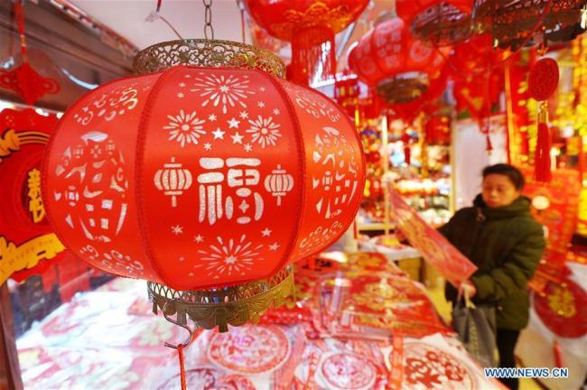 Une femme choisit des décorations de la fête du Printemps sur un marché de Qingdao, dans la province du Shandong (est de la Chine), le 26 janvier 2019.