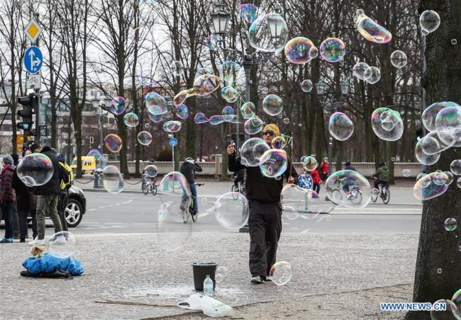 Un artiste fait des bulles de savon près de la porte de Brandebourg à Berlin, capitale de l'Allemagne, le 12 mars 2019. (Xinhua/Shan Yuqi)