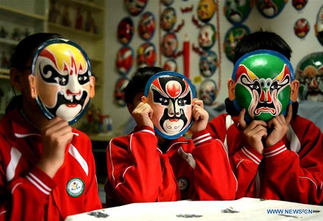 Trois élèves portent des masques de l'opéra de Pékin dans la résidence de Zhang Zhi, à Shijiazhuang, dans la province chinoise du Hebei (nord), le 12 avril 2019. Zhang Zhi, un retraité âgé de 82 ans, a réalisé plus de 1 000 masques de l'opéra de Pékin après sa retraite au cours des 25 dernières années. Il se consacre à promouvoir cet art. (Xinhua/Chen Qibao)
