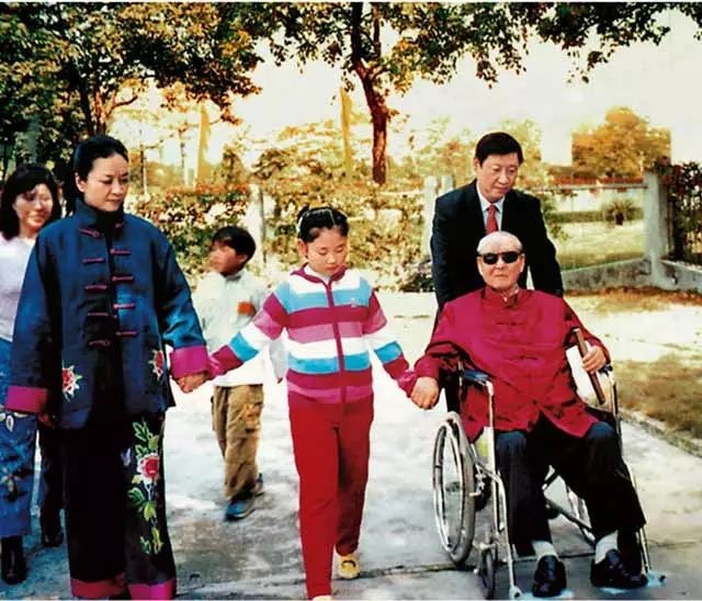 Dans cette photo, Xi Jinping se promène avec son père Xi Zhongxun en fauteuil roulant, sa femme Peng Liyuan et leur fille
