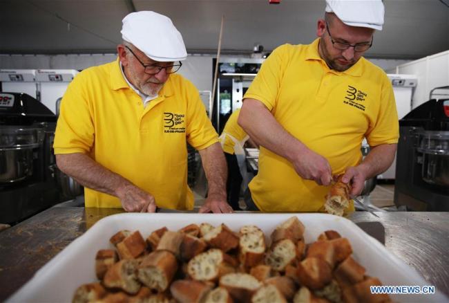 Des boulangers coupent des baguettes lors de la fête du Pain à Paris, en France, le 11 mai 2019. La 24e édition de la fête du Pain est organisée à Paris du 11 au 19 mai sur la Place Louis-Lépine, près de la cathédrale Notre-Dame. (Photo : Gao Jing)<br/><br/>