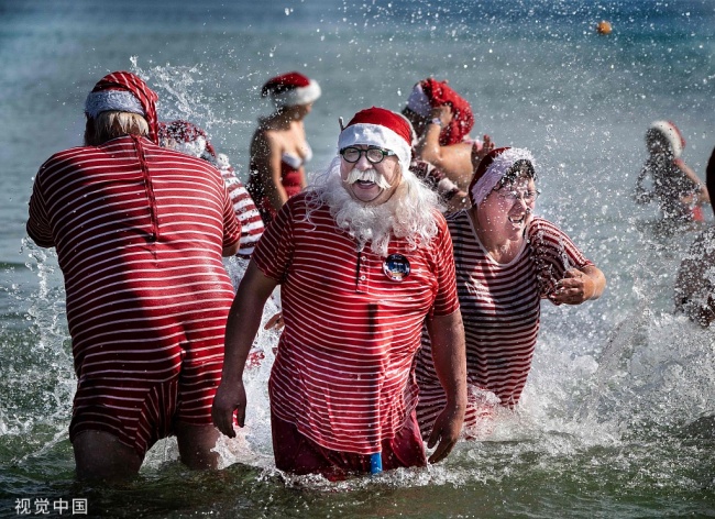 Des nageurs profitent de leur baignade annuelle en eau salée à la plage de Bellevue, le 23 juillet 2019, en marge du Congrès mondial des Pères Noël, qui a eu lieu du 22 au 25 juillet à Bakken, au nord de Copenhague, au Danemark. (Photo / VCG)