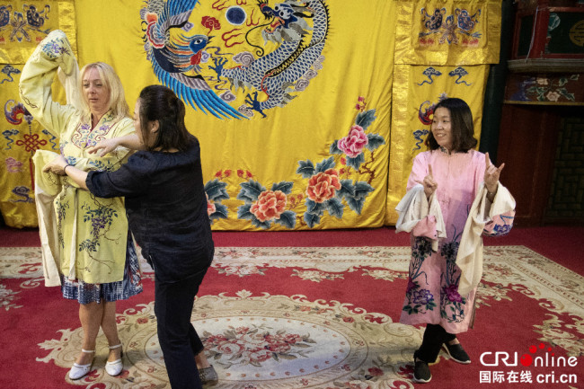 Smiljana Vlajic (à gauche), directrice du centre culturel de la province autonome de Vojvodine en Serbie, et Bae In Sun (à droite), chef du groupe sur les nouvelles chinoises du département international de l'Economie asiatique en République de Corée, apprennent l’opéra de Beijing sur scène.