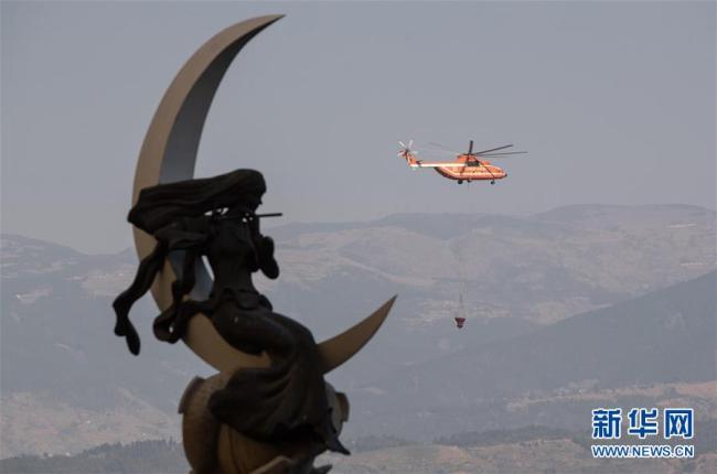 Un hélicoptère apportant de l’eau s’envole vers le site de l’incendie, le 31 mars, à Xichang.