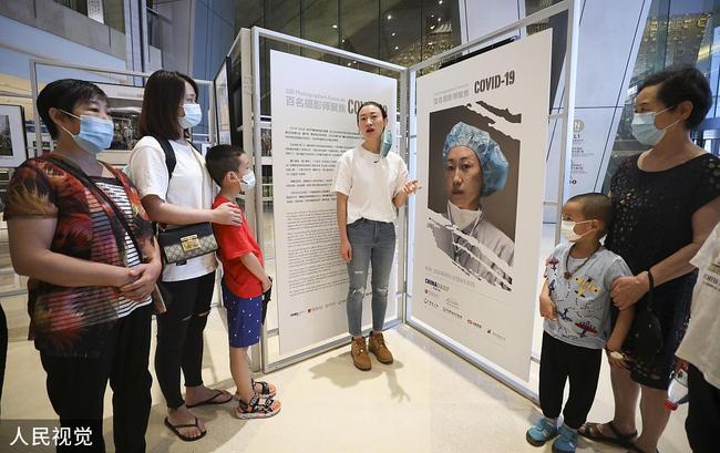 Des gens visitent une exposition intitulée "100 photographes se focalisent sur le COVID-19" et présentant 80 photos prises par les meilleurs photographes chinois pendant la pandémie de COVID-19, au China World Mall, à Beijing, capitale chinoise, le 1er août 2020.