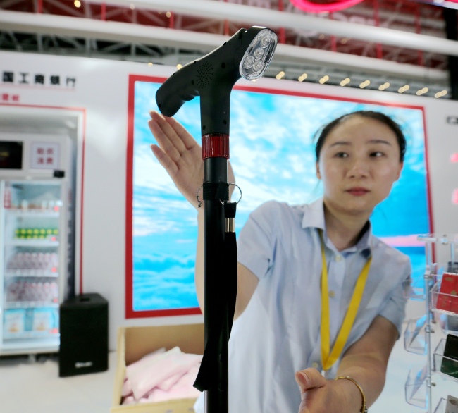 Une employée en train de présenter une canne doté d’une puce qui peut être utilisée comme outil de paiement, le 16 juin, au Salon de l’économie numérique de l’Ouest, à Xi’an.