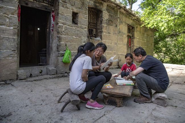 Ο Κινέζος δάσκαλος Τσουί Λιανρουί (2ος αριστερά) με τον διευθυντή του σχολείου Τζάο Τζιντσένγκ βοηθούν τους μαθητές στο χωριό Νανπέι στην κομητεία Λινγκτσάνγκ, στην επαρχία Σανσί της βόρειας Κίνας, στις 31 Μαΐου 2020. (Φωτογραφία / Xinhua)
