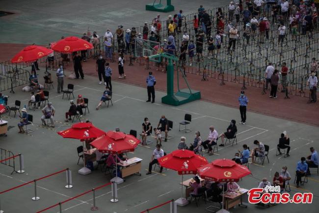 Πολίτες που φορούν μάσκες προσώπου περιμένουν στη σειρά για να λάβουν δοκιμές νουκλεϊκών οξέων στον προσωρινό χώρο δειγματοληψίας σε ένα δημοτικό σχολείο στην περιοχή Τσαογιάνγκ στο Πεκίνο, πρωτεύουσα της Κίνας. Το δημοτικό σχολείο μετατράπηκε προσωρινά σε τόπο δοκιμών νουκλεϊκών οξέων για τους κατοίκους της περιοχής. (Φωτογραφία / China News Service)