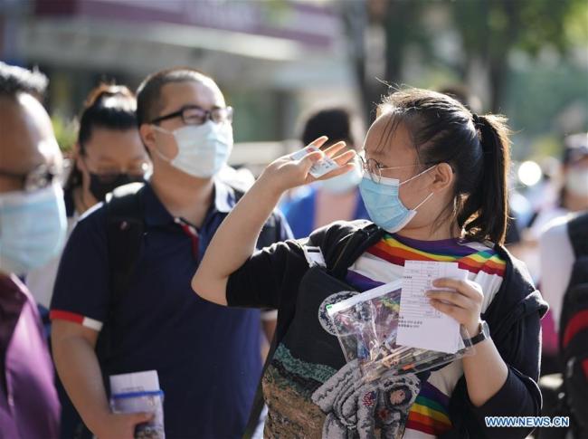 Μια εξεταζόμενη ετοιμάζει να μπει στον χώρο των εξετάσεων στο 8ο Λύκειο στο Πεκίνο, πρωτεύουσα της Κίνας, στις 7 Ιουλίου 2020. (Xinhua/Xing Guangli)<br>