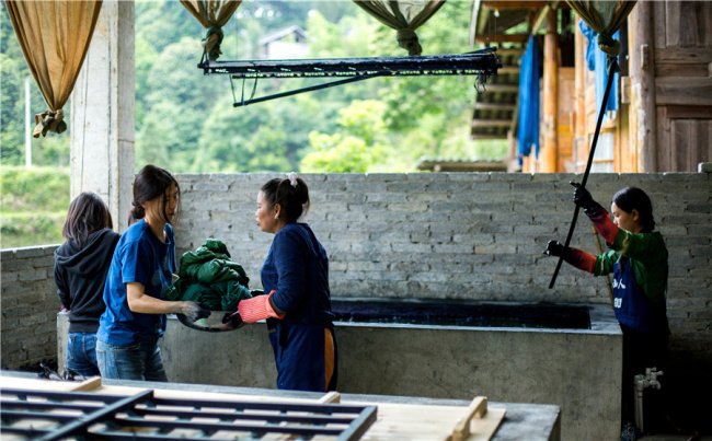 Οι γυναίκες της φυλής Ντονγκ εργάζονται στην βαφή παραδοσιακού υφάσματος. [Φωτογραφία από τον Fu Jianbin / Για την Κίνα καθημερινά] 