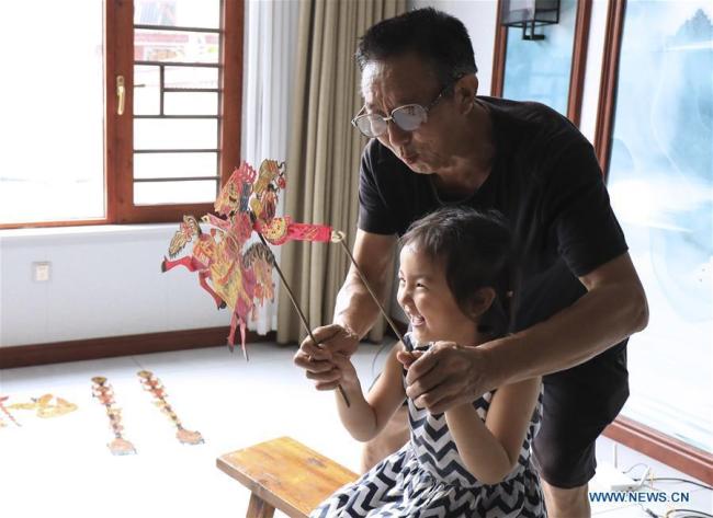 Ο καλλιτέχνης Τσάι Σαντσούν και η εγγονή του παίζουν με μια φιγούρα στο σπίτι στο χωριό Ντουτσούν της κομητείας Γιανγκσιάν, που βρίσκεται στην επαρχία Σαανσί της βορειοδυτικής Κίνας, 1η Αυγούστου 2020. (φωτογραφία/Xinhua)