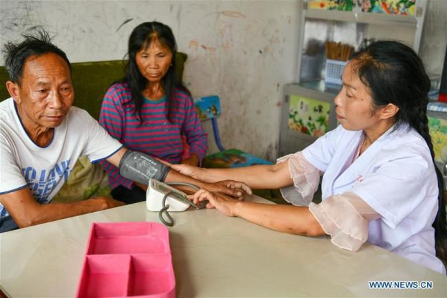 Η Λουό Μου μετρά την αρτηριακή πίεση για έναν χωρικό στο χωριό Τσουιγουέι της κομητείας Λονγκλί, στην αυτόνομη περιφέρεια Τσιενάν Μπουγί-Μιάο στην επαρχία Γκουιτζόου της νοτιοδυτικής Κίνας, 18 Αυγούστου 2020.