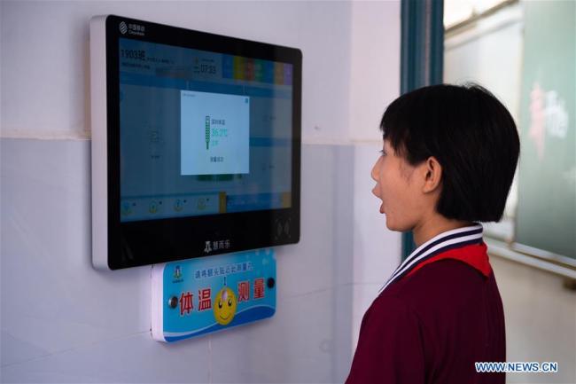 Μαθήτρια σε έλεγχο της θερμοκρασίας πριν μπει στην τάξη στο γυμνάσιο Νταογού του Λιουγιάνγκ στην πόλη Τσανγκσά, πρωτεύουσα της επαρχίας Χουνάν στην κεντρική Κίνα, στις 31 Αυγούστου 2020.