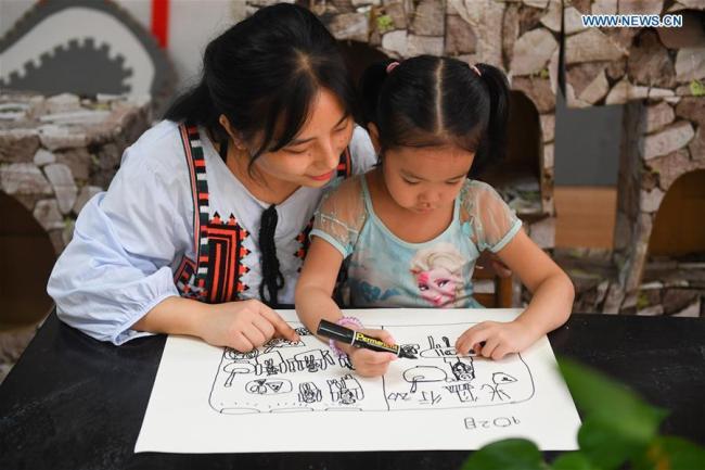 Μια δασκάλα ζητά από έναν μαθητή να σχεδιάσει μια εικόνα για τα τρόφιμα σε ένα νηπιαγωγείο στην Τσανγκσά, στην επαρχία Χουνάν της κεντρικής Κίνας, στις 2 Σεπτεμβρίου 2020.
