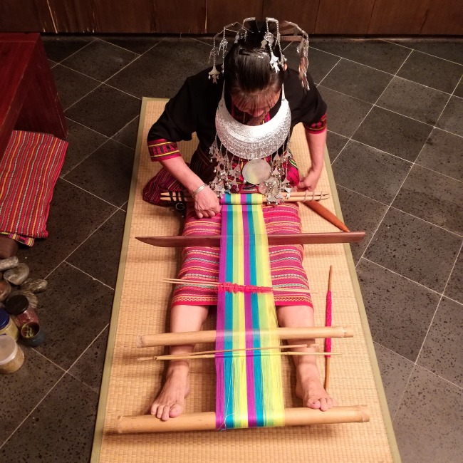 Γυναίκα με παραδοσιακή ενδυμασία της φυλής των Λι, που υφαίνει στον τυπικό αργαλειό των Λι που δένεται γύρω από την μέση και κρατιέται στην θέση του με τα πόδια (φωτ. Εύα Παπαζή, 20 Σεπτεμβρίου 2020)