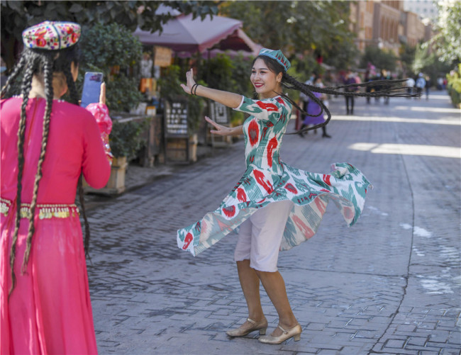 Μια γυναίκα χορεύει σε έναν δρόμο στην Παλιά Πόλη του Κασγκάρ. [Φωτογραφία / XINHUA]