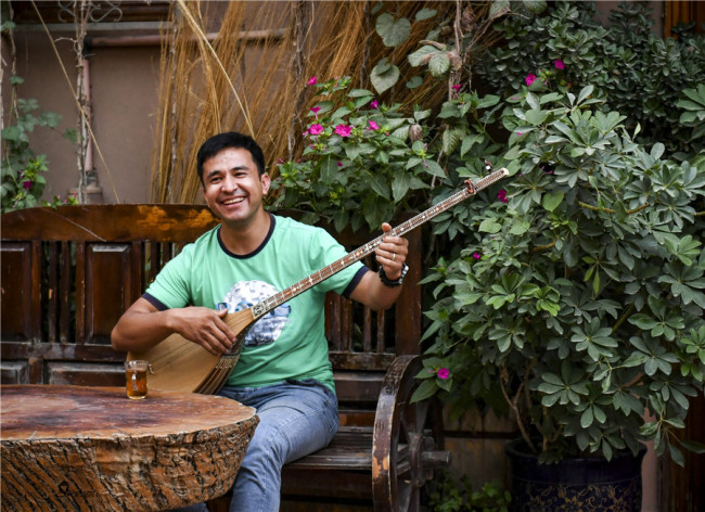 Ένας άντρας παίζει το ντουτάρ, ένα παραδοσιακό μουσικό όργανο και τραγουδά έξω από ένα κτίριο στην Παλιά Πόλη. [Φωτογραφία / XINHUA]