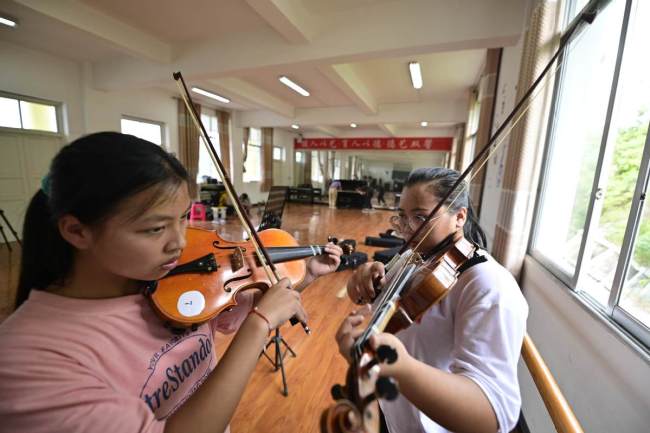 Στην τάξη μουσικής ενός γυμνασίου στο νομό Τσονγκτζιάνγκ, στην επαρχία Γκουιτζόου της νοτιοδυτικής Κίνας, οι μαθητές μαθαίνουν να παίζουν βιολί. [Φωτογραφία από τον Wu Dejun / Για το chinadaily.com.cn]
