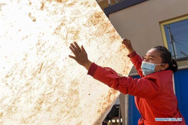 Τεχνίτρια ελέγχει στον ήλιο ένα κομμάτι χαρτί που έγινε από φλοιό μουριάς στην κομητεία Μογιού του Χοτάν, που βρίσκεται στην Αυτόνομη Περιοχή Σιντζιάνγκ Ουιγκούρ της βορειοδυτικής Κίνας, την 1η Νοεμβρίου 2020. 