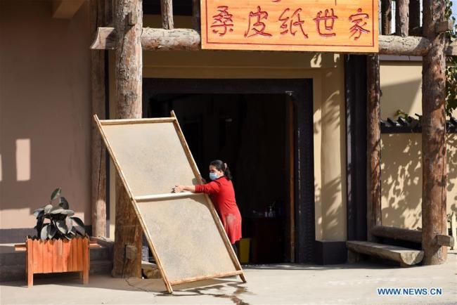 Τεχνίτρια στεγνώνει ένα κομμάτι χαρτί από φλοιό μουριάς στον ήλιο, στην Μογιού του Χοτάν, που βρίσκεται στην Αυτόνομη Περιοχή Σιντζιάνγκ Ουιγκούρ της βορειοδυτικής Κίνας, την 1η Νοεμβρίου 2020. 