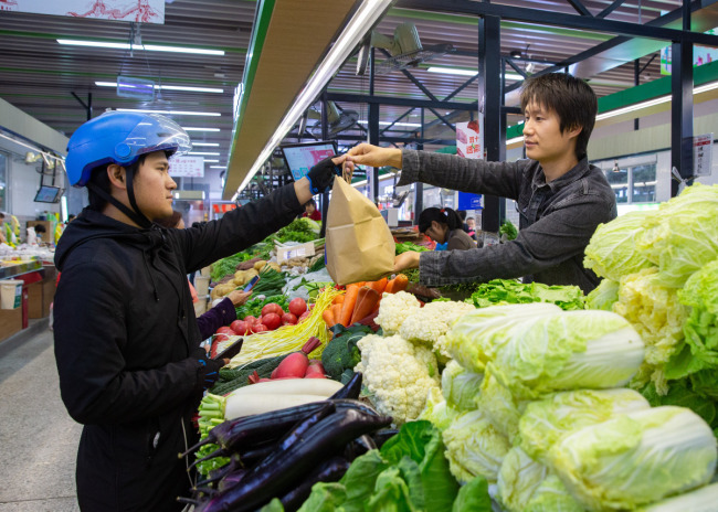 Ο Γουάνγκ Σιαογιού παραδίδει ένα γεύμα γεμάτο μυστήριο σε έναν διανομέα στην αγορά της Ναντζίνγκ, την 1η Νοεμβρίου 2020. [Φωτογραφία: CNSPHOTO]