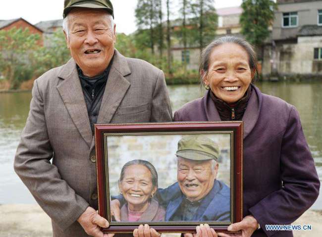Ένα ζευγάρι ντόπιων χαμογελά καθώς κρατούν τη φωτογραφία τους στο χωριό Σιαγουέι της περιοχής Γιοουλάν, κοντά στην πρωτεύουσα Ναντσάνγκ, στην επαρχία Τζιανγκσί της ανατολικής Κίνας, στις 22 Νοεμβρίου 2020.