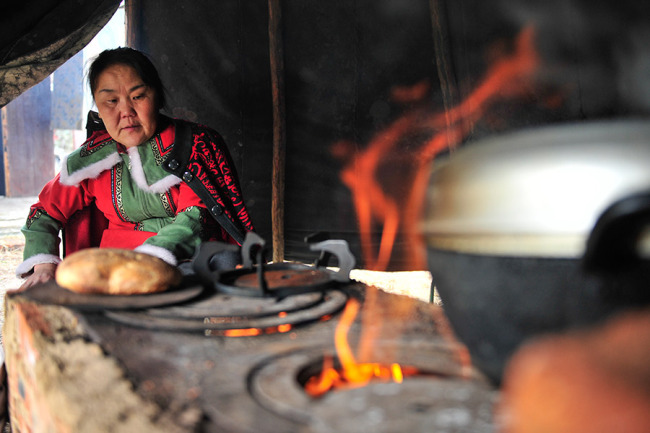 Η Σουογιουλάν φτιάχνει ρώσικο ψωμί στο Αολουγκουγιά των Εβένκι. Το ψωμί αυτό που φτιάχνεται από αλεύρι και γάλα ταράνδου, είναι παραδοσιακά το κύριο τρόφιμο των Εβένκι. [Φωτογραφία από WANG WEI / FOR CHINA DAILY]