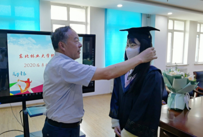 Στην φωτογραφία, ο Γκενγκ Γιουντέ, πρύτανης της Σχολής Οικονομικών και Διοίκησης, τοποθετεί το καπέλο αποφοίτησης στην Λι Μιν, μετά την παρουσίαση της πτυχιακής της στο Βορειανατολικό Πανεπιστήμιο Δασοκομίας στο Χάρμπιν, πρωτεύουσα της επαρχίας Χεϊλοτζιάνγκ, την 1η Ιουνίου. [Παρέχεται στο chinadaily.com.cn]