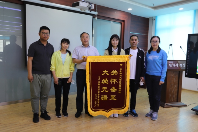 Η Λιν Μιν και οι γονείς της, προσφέρουν ένα μεταξωτό λάβαρο ευγνωμοσύνης προς την Σχολή Οικονομίας και Διοίκησης, την 1η Ιουνίου. [Φωτογραφία παρέχεται στο chinadaily.com.cn]