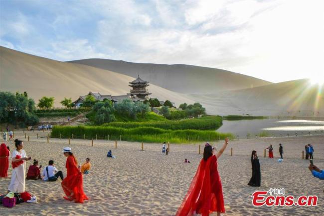 Οι τουρίστες κατευθύνονται προς τη Λίμνη της Ημισελήνου στο Ντουνχουάνγκ της επαρχίας Γκανσού της βορειοδυτικής Κίνας. (Φωτογραφία / China News Service)
