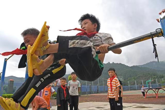 Школьники поселка Сичэн Гуанси-Чжуанского автономного района занимаются спортом на турнике.