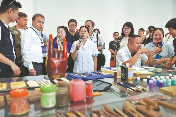 Η Τσεν Χουιλί ενώ εξηγεί το έργο της διατήρησης σε διεθνείς επισκέπτες στο εργαστήριο συντήρησης της Ακαδημίας Νταζού, στο Τσονγκτσίνγκ. [Τζιανγκ Ντονγκ/China Daily]