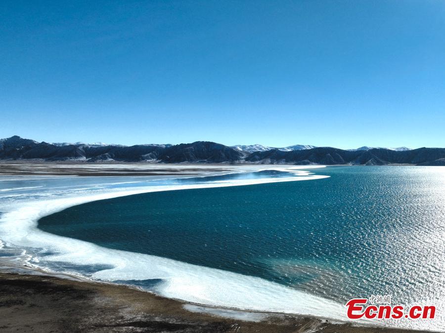 Χειμερινό τοπίο σαν ζωγραφιά της μισοπαγωμένης λίμνης Ντονγκτζί Τσουονά με γαλαζοπράσινα νερά στην κομητεία Μαντούο, της Αυτόνομης Νομαρχίας Γκολόγκ που βρίσκεται στην επαρχία Τσινγκχάι της βορειοδυτικής Κίνας. (Φωτογραφία: China News Service/Zhao Linsong)