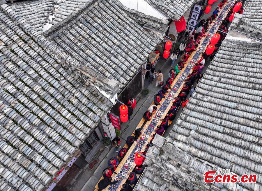 Τουρίστες απολαμβάνουν ένα λαϊκό συμπόσιο σε μακρύ τραπέζι κατά μήκος ενός δρόμου στην πόλη Χουανσάν, στην επαρχία Ανχούι της ανατολικής Κίνας, 30 Ιανουαρίου 2024. (Φωτογραφία: China News Service/Shi Yalei)
