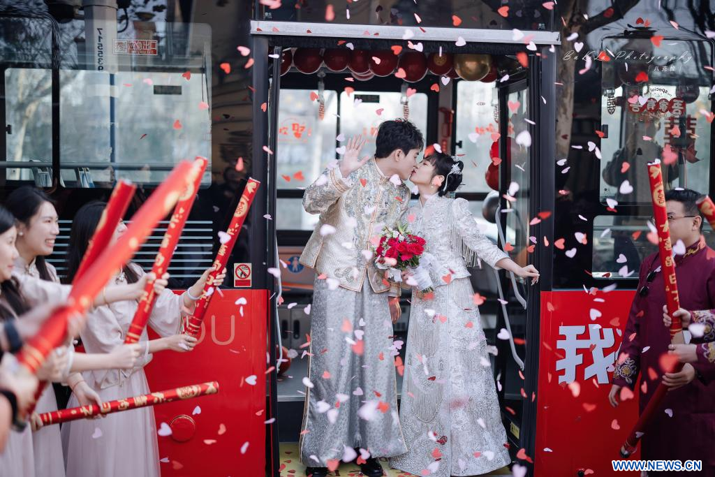 Φωτογραφία από τις 9 Δεκεμβρίου 2023, των νεόνυμφων Μα Γιουσουάν και Τσάι Γιανγκ που ποζάρουν για φωτογραφία σε ένα γαμήλιο λεωφορείο, στο Τσινγκντάο, στην επαρχία Σαντόνγκ της ανατολικής Κίνας. (Xinhua)