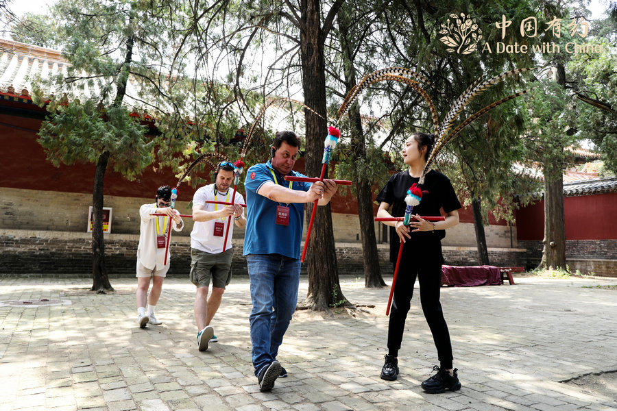 Μέλη της διεθνούς περιοδείας "Ένα ραντεβού με την Κίνα 2024 – Γνωριμία με το Σαντόνγκ", εξασκούνται στον χορό γιγού στο ναό του Κομφούκιου στο Τσουφού, στην επαρχία Σαντόνγκ της Ανατολικής Κίνας, στις 3 Ιουνίου 2024. [Φωτογραφία από chinadaily.com.cn]
