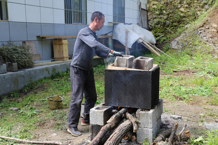 图片默认标题_fororder_一名养殖户正在对自家新制的蜂箱进行沸水消毒工作