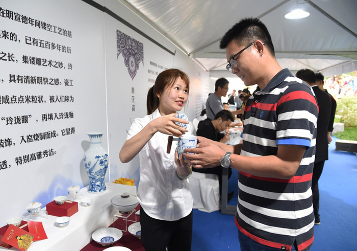 图片默认标题_fororder_10-工作人员在“江西日”活动中向游客介绍景德镇陶瓷茶杯